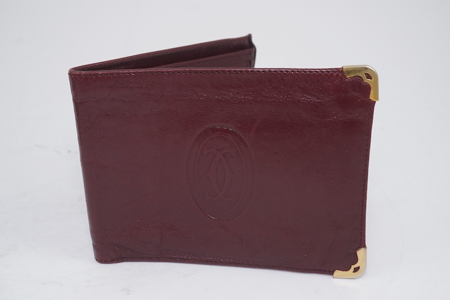 An assortment of Must de Cartier bordeaux leather accessories